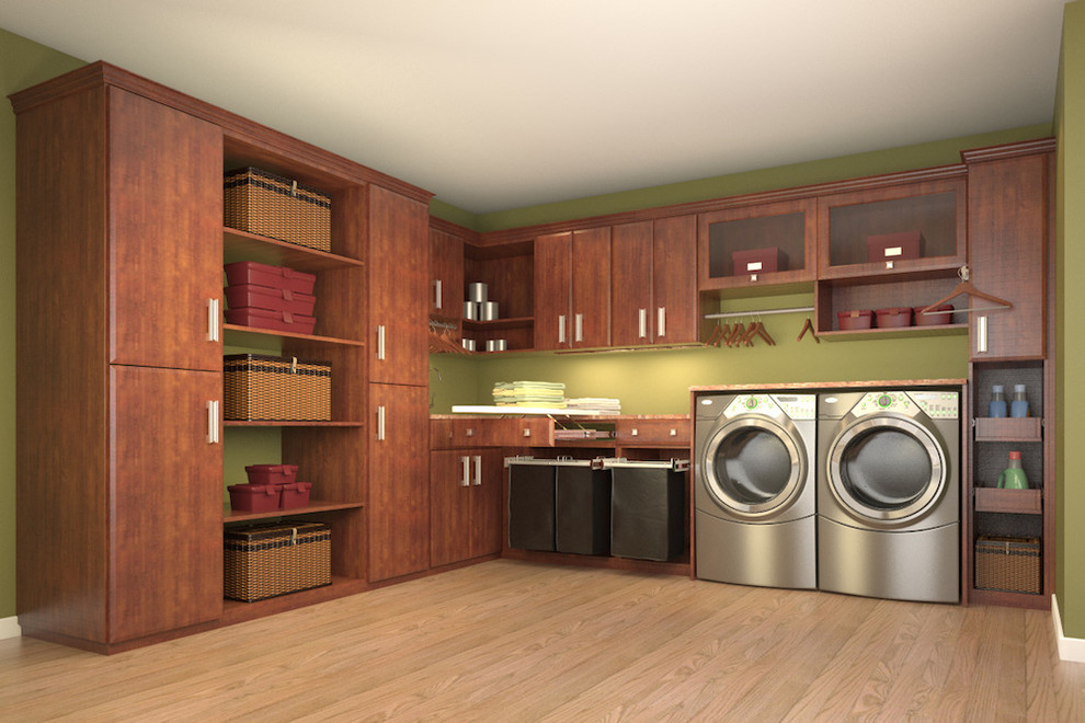 Photo of a medium sized contemporary l-shaped utility room in Los Angeles with flat-panel cabinets, medium wood cabinets, green walls, light hardwood flooring and a side by side washer and dryer.