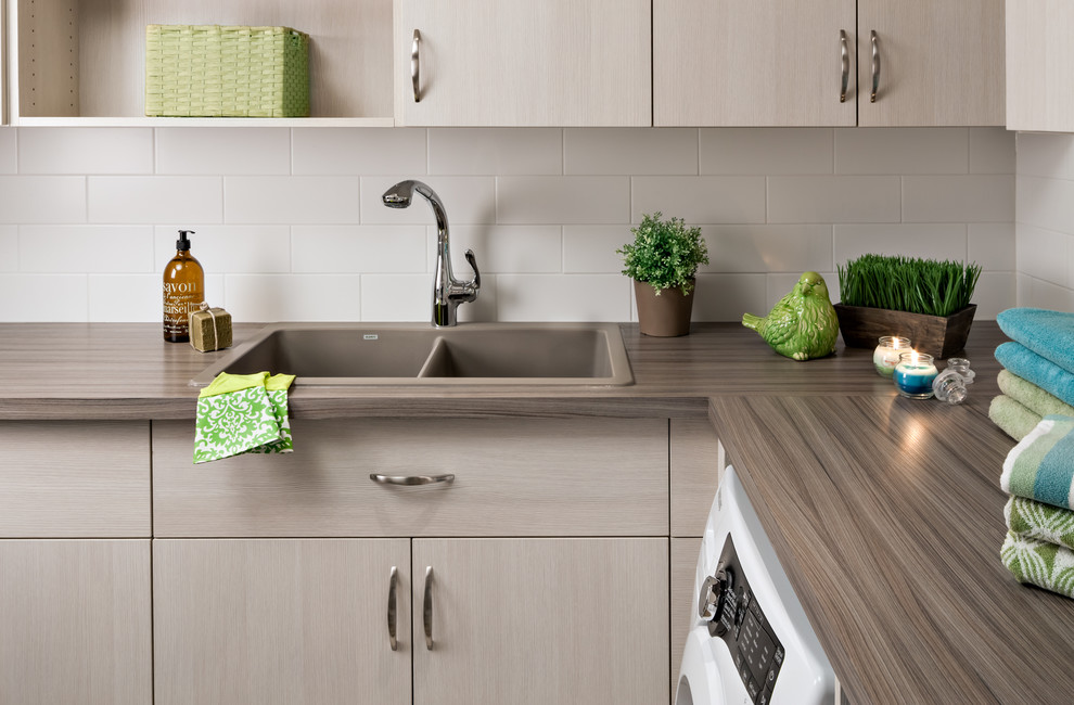 Inspiration for a large contemporary utility room in Toronto with a built-in sink, flat-panel cabinets, light wood cabinets, laminate countertops, beige walls and a side by side washer and dryer.