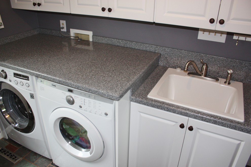 Foto di una sala lavanderia classica di medie dimensioni con ante bianche, lavatrice e asciugatrice affiancate, lavello da incasso, ante con bugna sagomata, top in laminato, pareti grigie e top grigio