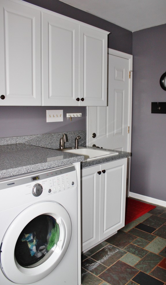 Inredning av en klassisk mellanstor grå linjär grått tvättstuga enbart för tvätt, med en nedsänkt diskho, luckor med upphöjd panel, vita skåp, laminatbänkskiva, grå väggar och en tvättmaskin och torktumlare bredvid varandra