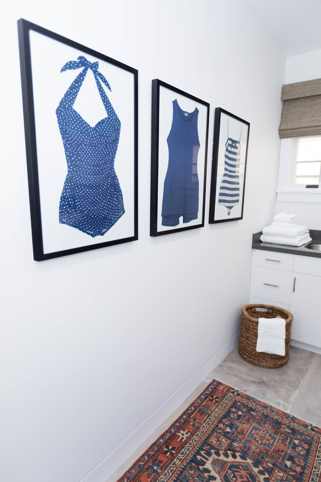 Exempel på en liten klassisk l-formad tvättstuga enbart för tvätt, med en undermonterad diskho, släta luckor, vita skåp, vita väggar, en tvättmaskin och torktumlare bredvid varandra och beiget golv