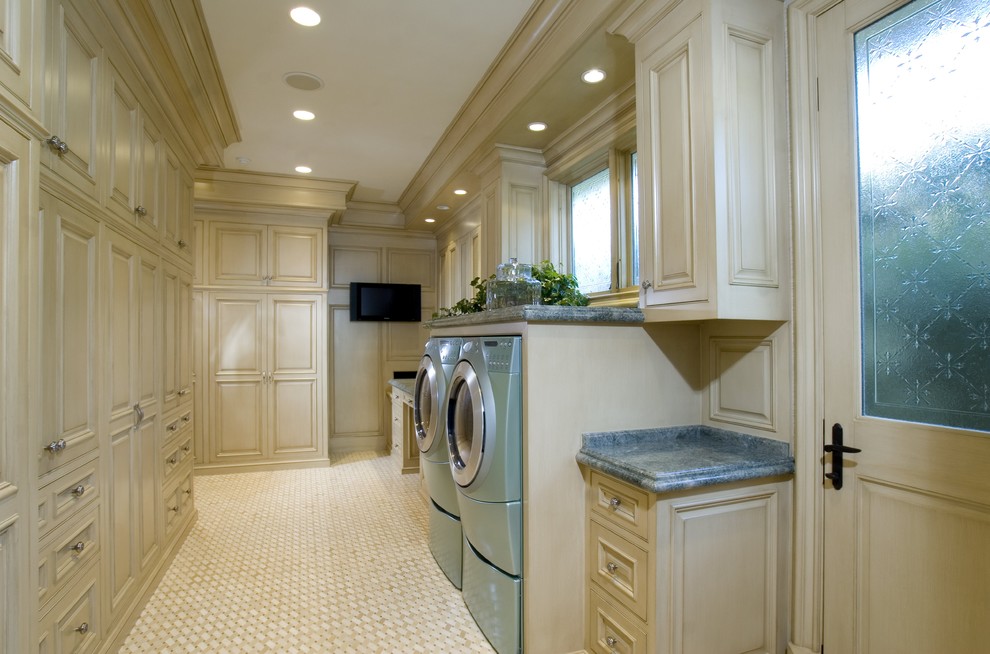 Große Klassische Waschküche in U-Form mit weißen Schränken, beigem Boden, profilierten Schrankfronten, Granit-Arbeitsplatte, beiger Wandfarbe, Porzellan-Bodenfliesen, Waschmaschine und Trockner nebeneinander und blauer Arbeitsplatte in Orange County