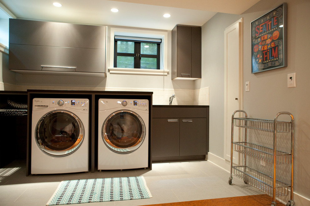 Immagine di una sala lavanderia contemporanea di medie dimensioni con lavello sottopiano, ante grigie, top in quarzo composito, pareti grigie, pavimento in gres porcellanato e lavatrice e asciugatrice affiancate