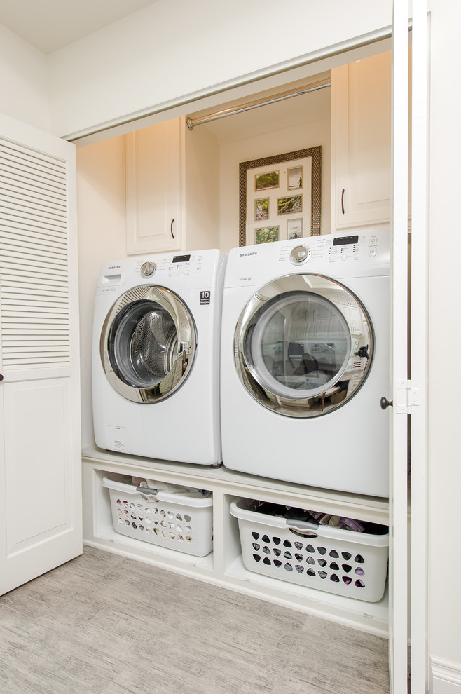 Photo of a small traditional single-wall laundry cupboard in Los Angeles with raised-panel cabinets, white cabinets, engineered stone countertops, white walls, porcelain flooring and a side by side washer and dryer.