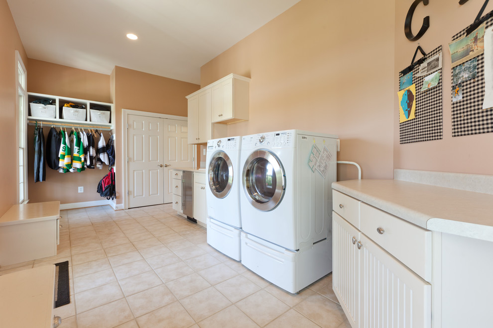 Immagine di una lavanderia multiuso tradizionale con ante lisce, lavatrice e asciugatrice affiancate, lavello da incasso e ante beige