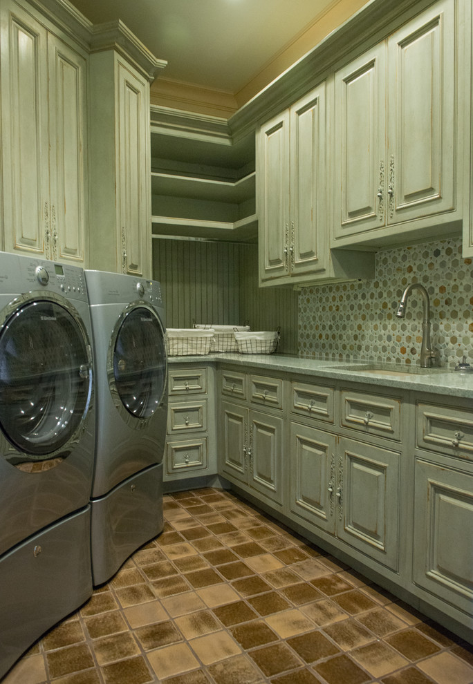 Esempio di una grande lavanderia multiuso rustica con lavello a vasca singola, ante con bugna sagomata, ante con finitura invecchiata, lavatrice e asciugatrice affiancate e pareti verdi