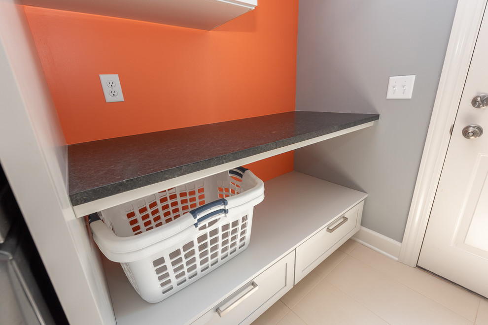 This is an example of a small classic single-wall utility room in Indianapolis with recessed-panel cabinets, grey cabinets, granite worktops, grey walls, ceramic flooring, a stacked washer and dryer, white floors and black worktops.