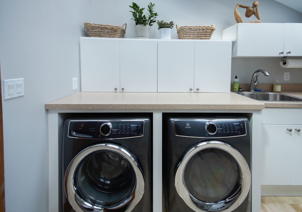Large transitional l-shaped ceramic tile and beige floor dedicated laundry room photo in Cincinnati with flat-panel cabinets, white cabinets, laminate countertops, white walls, a side-by-side washer/dryer, a drop-in sink and beige countertops
