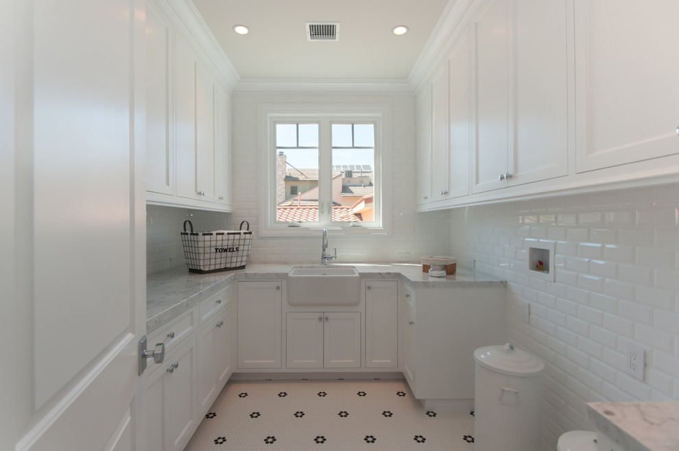 Dedicated laundry room - mid-sized traditional u-shaped ceramic tile dedicated laundry room idea in Los Angeles with a farmhouse sink, shaker cabinets, white cabinets, marble countertops and a side-by-side washer/dryer