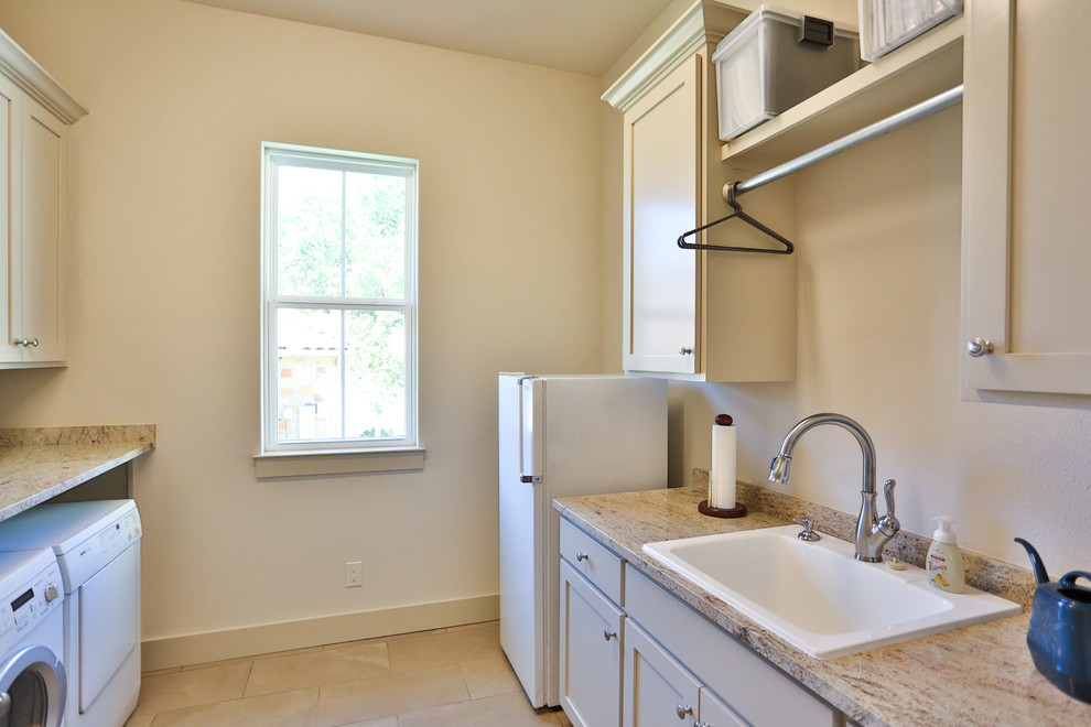 Example of a small classic galley porcelain tile and white floor dedicated laundry room design in Austin with a farmhouse sink, recessed-panel cabinets, beige cabinets, granite countertops, beige walls, a side-by-side washer/dryer and multicolored countertops