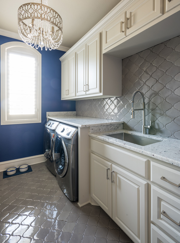 Zweizeilige, Mittelgroße Klassische Waschküche mit Unterbauwaschbecken, profilierten Schrankfronten, beigen Schränken, Granit-Arbeitsplatte, blauer Wandfarbe, Keramikboden und Waschmaschine und Trockner nebeneinander in Dallas