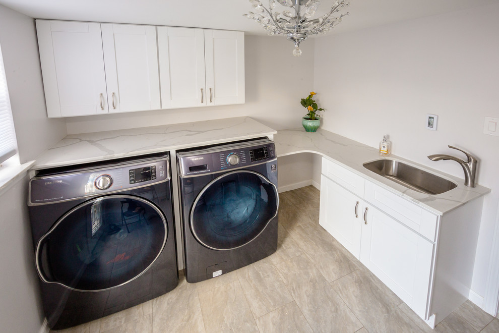 This is an example of a medium sized contemporary l-shaped utility room in Philadelphia with a submerged sink, engineered stone countertops, white walls, porcelain flooring, a side by side washer and dryer, shaker cabinets, white cabinets and brown floors.