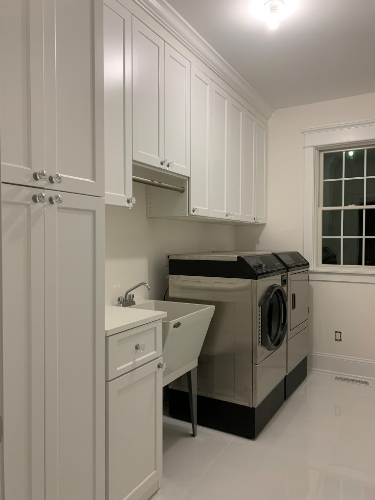 Inspiration for a large classic single-wall separated utility room in New York with an utility sink, shaker cabinets, white cabinets, a side by side washer and dryer and white worktops.