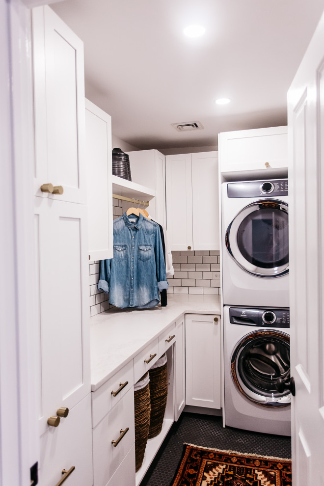Small mid-century modern l-shaped porcelain tile and black floor dedicated laundry room photo in Philadelphia with shaker cabinets, white cabinets, quartz countertops, white backsplash, subway tile backsplash, white walls, a stacked washer/dryer and white countertops