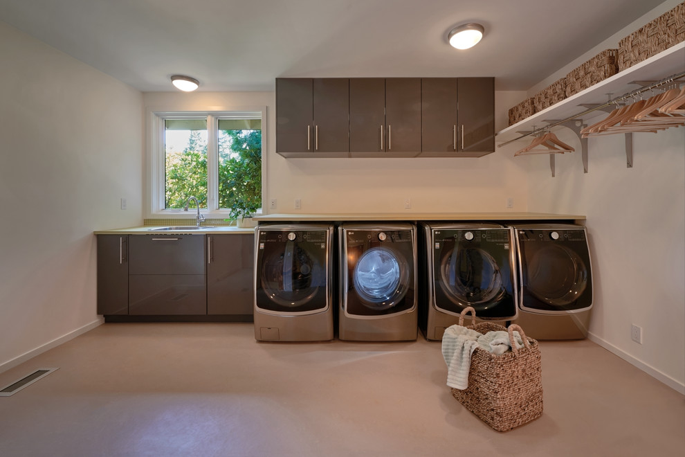 Idéer för mellanstora vintage l-formade tvättstugor enbart för tvätt, med en undermonterad diskho, släta luckor, grå skåp, laminatbänkskiva, vita väggar, linoleumgolv och en tvättmaskin och torktumlare bredvid varandra