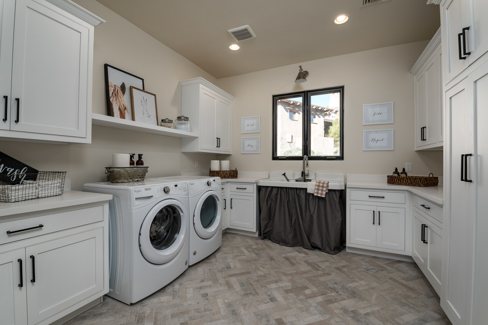 Idéer för en amerikansk beige u-formad tvättstuga enbart för tvätt, med en allbänk, skåp i shakerstil, vita skåp, beige väggar, en tvättmaskin och torktumlare bredvid varandra och beiget golv
