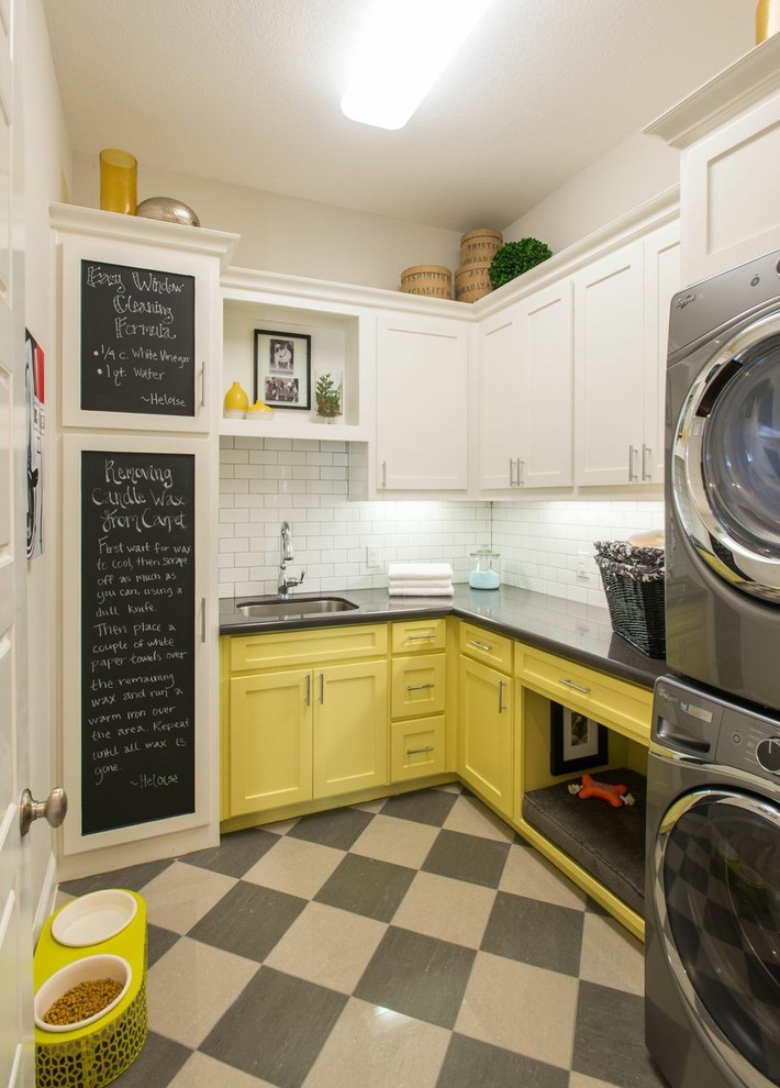 Ejemplo de lavadero en L tradicional con fregadero bajoencimera, armarios estilo shaker, puertas de armario amarillas, paredes blancas, lavadora y secadora apiladas y encimeras grises