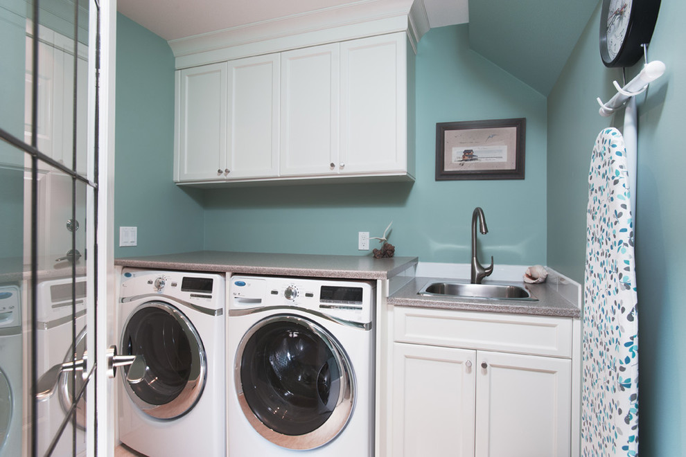 Esempio di una lavanderia multiuso di medie dimensioni con lavello da incasso, ante con riquadro incassato, ante bianche, pareti blu e lavatrice e asciugatrice affiancate