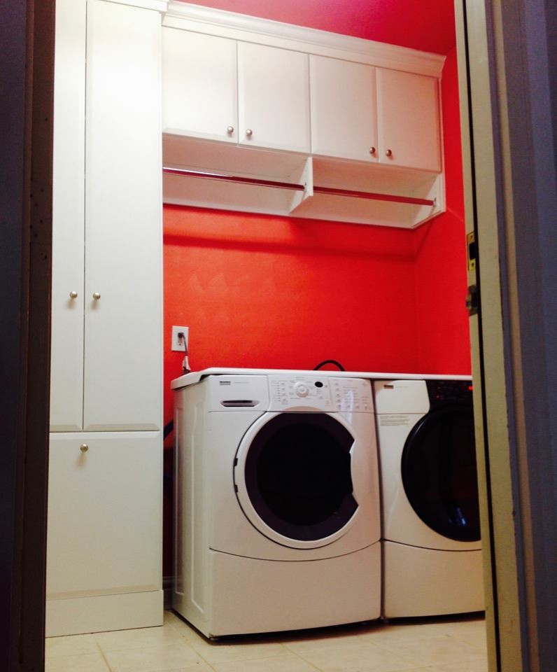 Kleine Moderne Waschküche mit Unterbauwaschbecken, weißen Schränken, roter Wandfarbe und Waschmaschine und Trockner nebeneinander in New York