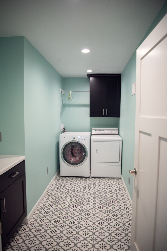 Bild på en stor funkis vita vitt tvättstuga enbart för tvätt, med en nedsänkt diskho, släta luckor, svarta skåp, laminatbänkskiva, gröna väggar, klinkergolv i keramik, en tvättmaskin och torktumlare bredvid varandra och flerfärgat golv