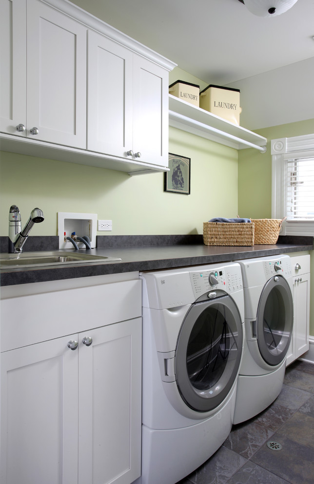 Immagine di una sala lavanderia classica di medie dimensioni con ante in stile shaker, ante bianche, pareti verdi, pavimento in ardesia, lavatrice e asciugatrice affiancate e lavello da incasso