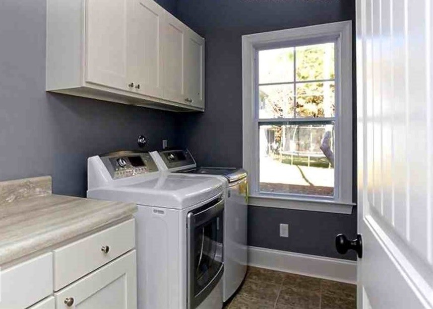 Classic single-wall utility room in Chicago with recessed-panel cabinets, white cabinets, laminate countertops, blue walls, ceramic flooring and a side by side washer and dryer.
