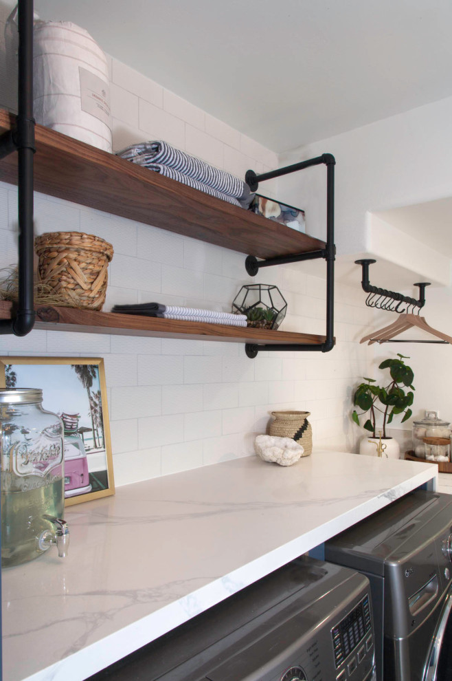 Mid-sized beach style l-shaped porcelain tile and gray floor dedicated laundry room photo in Denver with a farmhouse sink, recessed-panel cabinets, blue cabinets, quartz countertops, white walls, a side-by-side washer/dryer and white countertops
