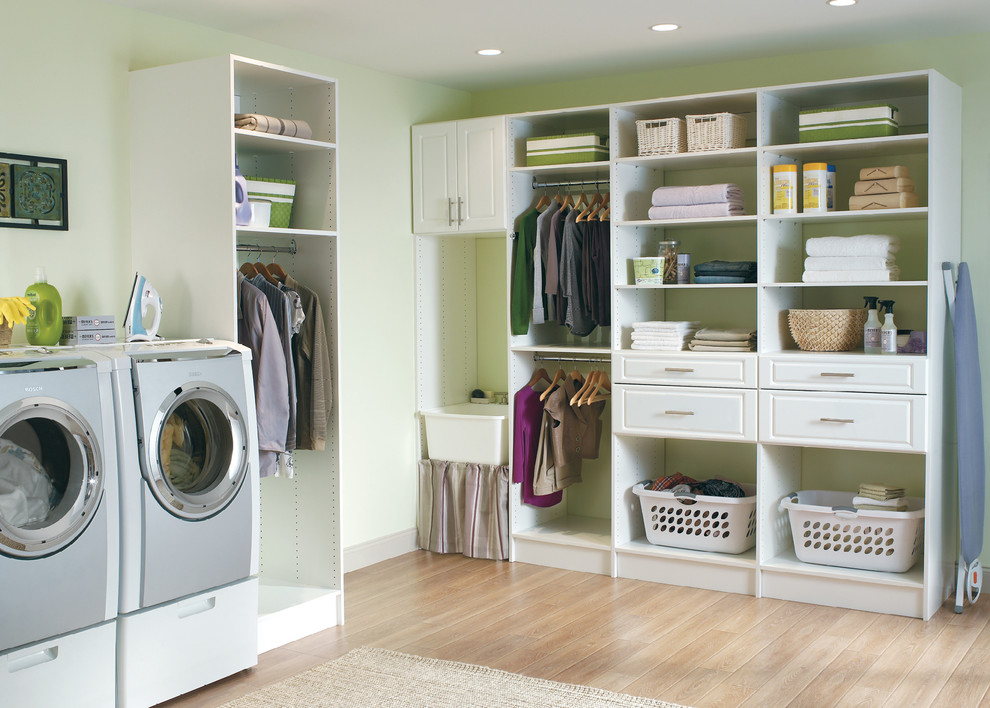 Diseño de lavadero en L tradicional de tamaño medio con armarios abiertos, puertas de armario blancas, encimera de acrílico, paredes verdes, suelo de madera oscura y lavadora y secadora juntas