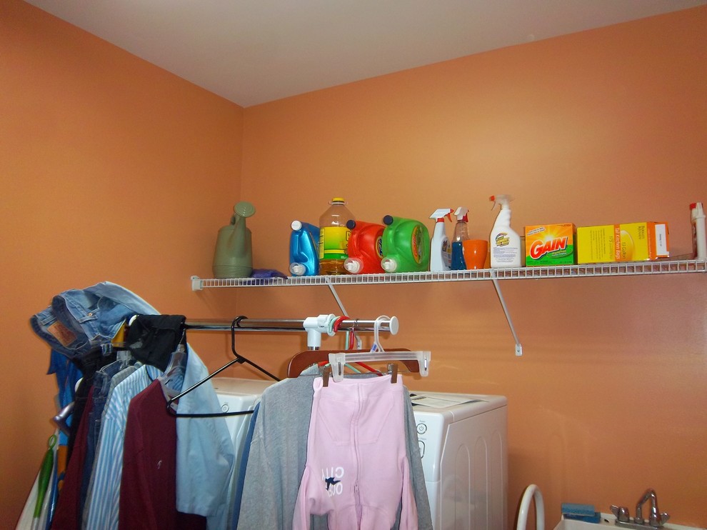 Idéer för en mellanstor modern linjär tvättstuga enbart för tvätt, med en allbänk, orange väggar och en tvättmaskin och torktumlare bredvid varandra