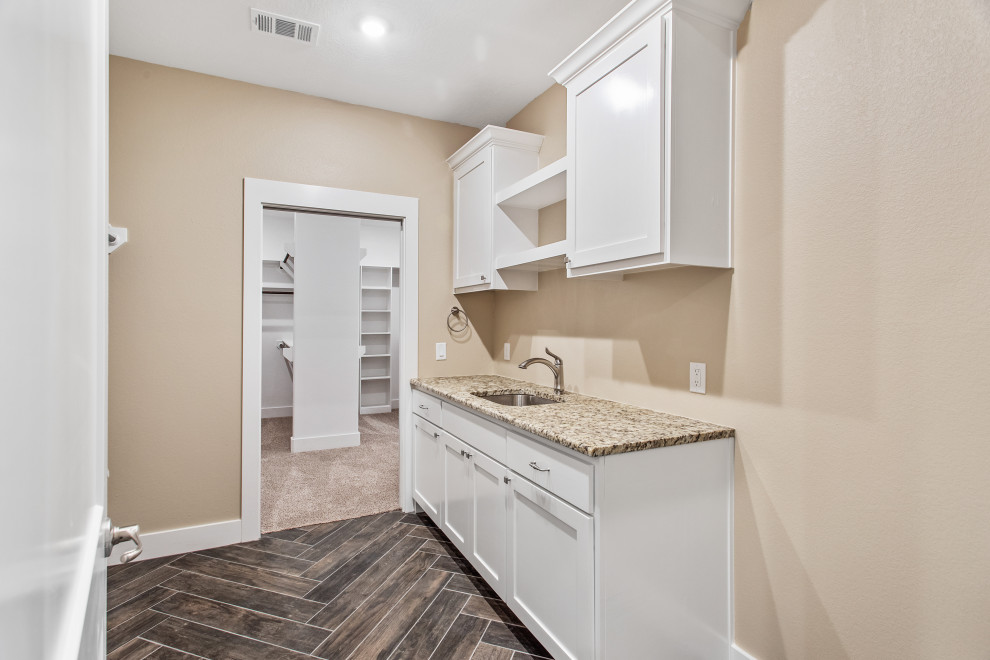 Foto di una lavanderia multiuso stile americano con top in granito, pareti beige, parquet scuro, lavatrice e asciugatrice affiancate, pavimento marrone e top multicolore