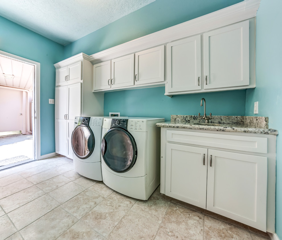 Idéer för mellanstora vintage tvättstugor, med en undermonterad diskho, skåp i shakerstil, vita skåp, granitbänkskiva, blå väggar, klinkergolv i keramik, en tvättmaskin och torktumlare bredvid varandra och brunt golv