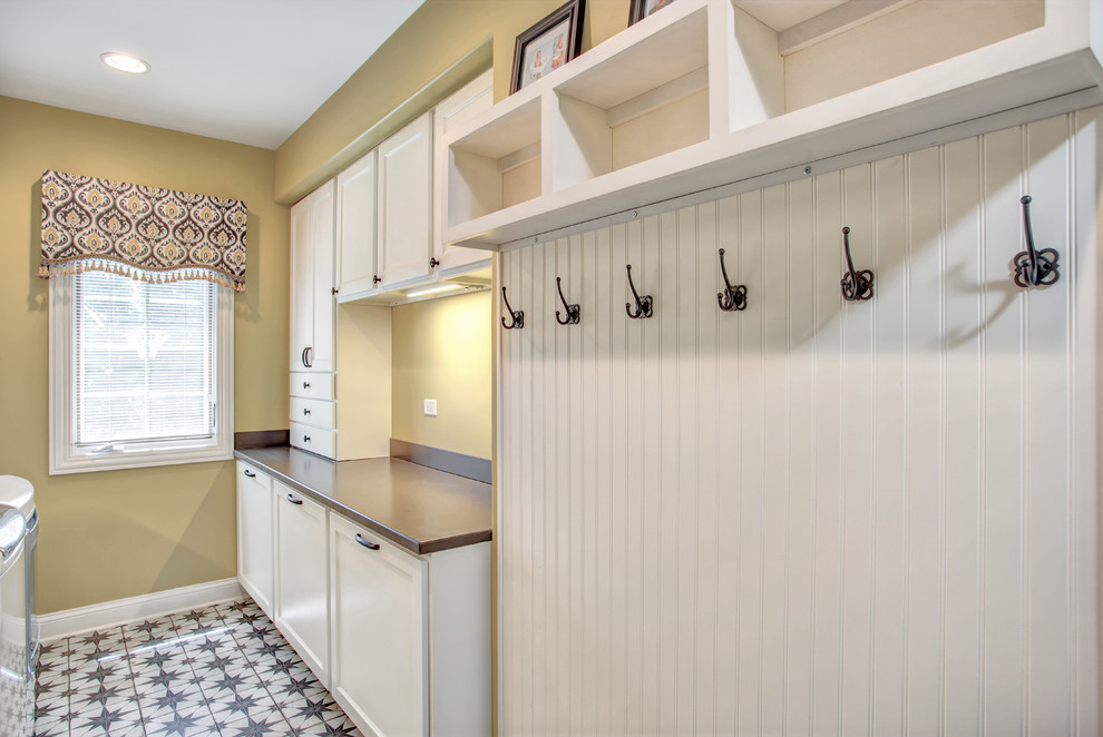 Example of a mid-sized classic galley ceramic tile and multicolored floor utility room design with an undermount sink, recessed-panel cabinets, white cabinets, solid surface countertops and a side-by-side washer/dryer