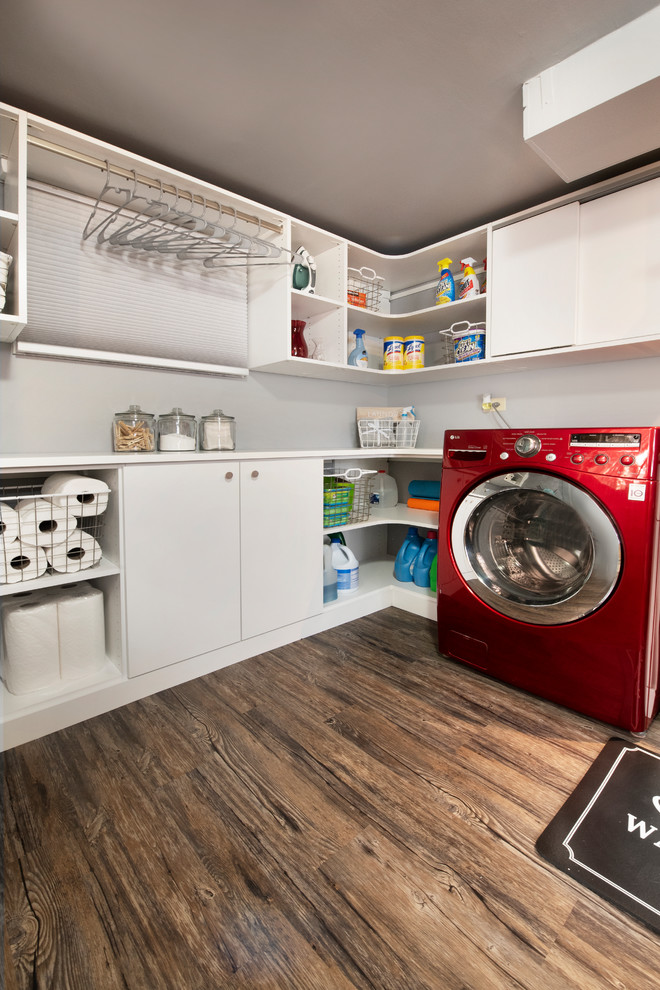 Immagine di una sala lavanderia minimalista di medie dimensioni con ante lisce, ante bianche, top in laminato, pareti grigie, pavimento in vinile, lavasciuga, pavimento marrone e top bianco