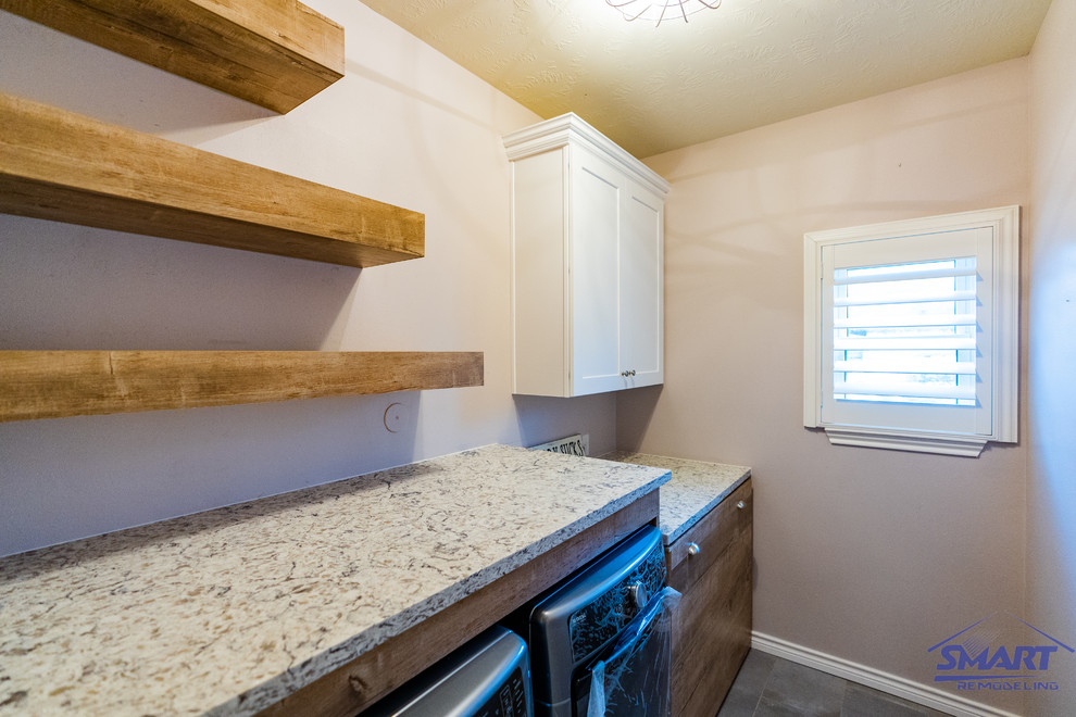 Small elegant single-wall ceramic tile, gray floor, coffered ceiling and wainscoting dedicated laundry room photo in Houston with medium tone wood cabinets, a side-by-side washer/dryer, beige countertops, a drop-in sink, shaker cabinets, quartzite countertops, beige backsplash and beige walls