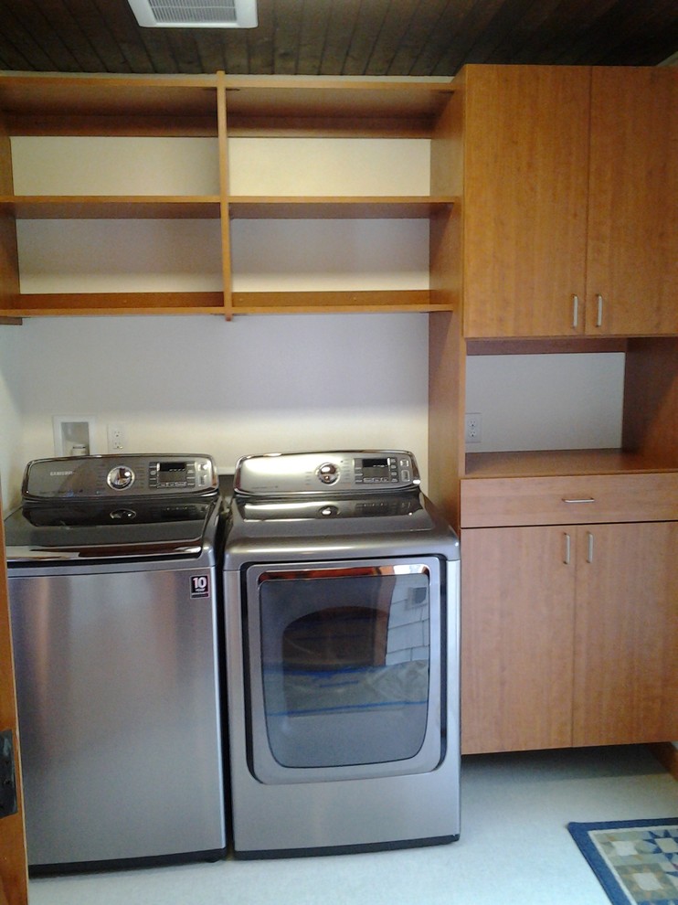 Photo of a small contemporary galley separated utility room in Seattle with flat-panel cabinets, medium wood cabinets, white walls, vinyl flooring and a side by side washer and dryer.