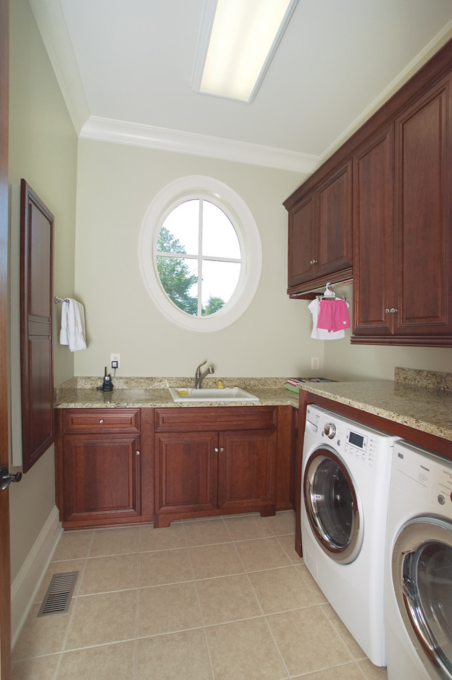 Mittelgroße Klassische Waschküche in L-Form mit Unterbauwaschbecken, profilierten Schrankfronten, dunklen Holzschränken, Granit-Arbeitsplatte, grauer Wandfarbe, Porzellan-Bodenfliesen und Waschmaschine und Trockner nebeneinander in Atlanta