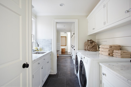 Premium RTA cabinets Canada – bright laundry room with white shaker cabinets, marble countertops, front-loading washer & dryer, shiplap walls and grey stone floors.