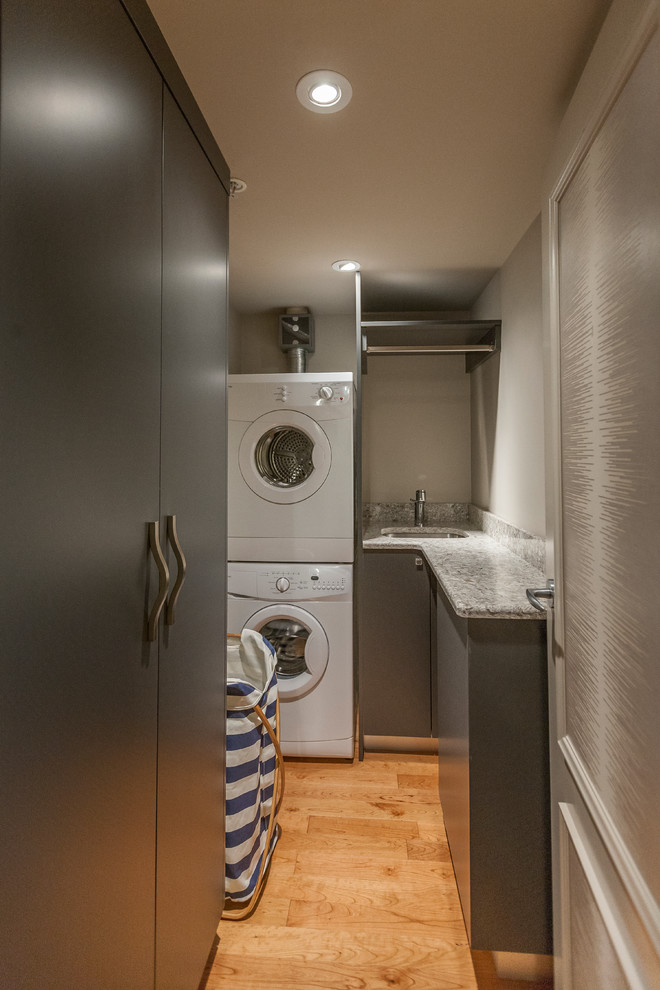 Inspiration för små parallella tvättstugor enbart för tvätt, med en undermonterad diskho, släta luckor, grå skåp, bänkskiva i kvarts, grå väggar, ljust trägolv och en tvättpelare