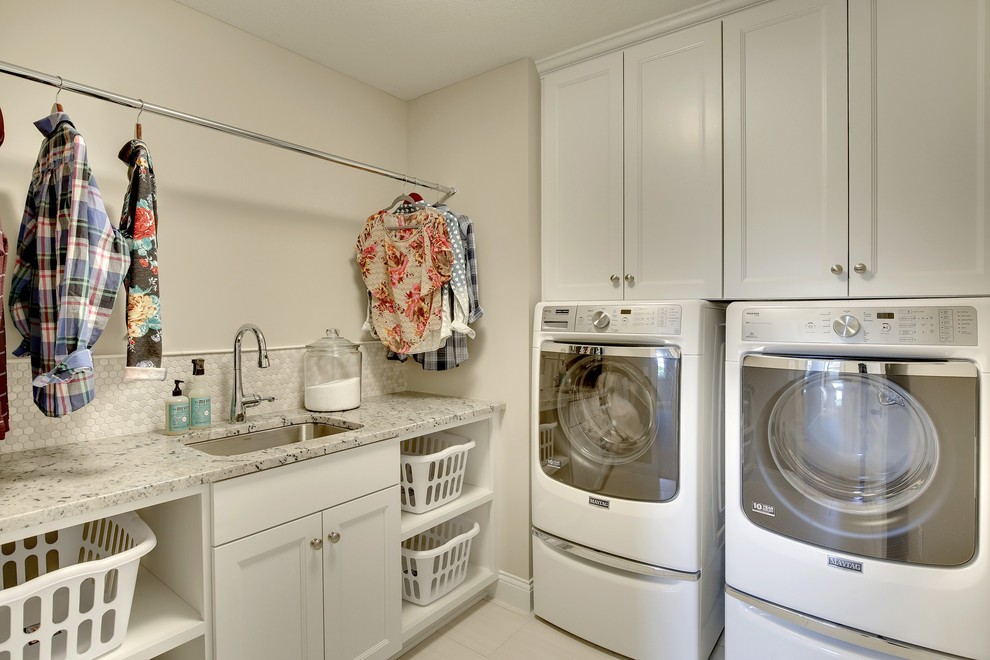 Idee per una grande sala lavanderia classica con lavello sottopiano, ante bianche, pareti beige, pavimento con piastrelle in ceramica, lavatrice e asciugatrice affiancate e ante con riquadro incassato