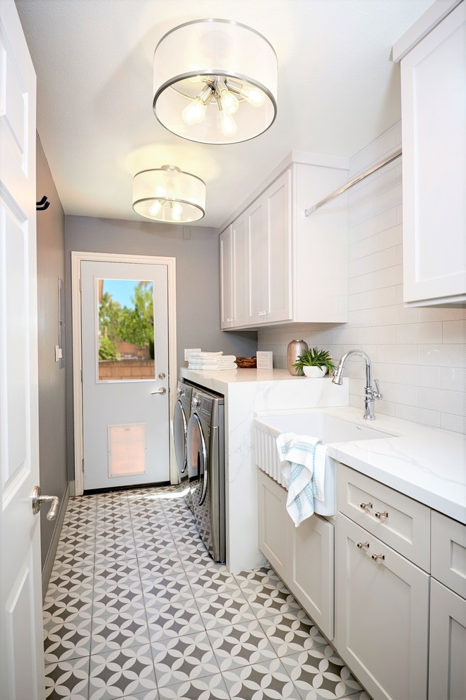 Utility room - small coastal single-wall ceramic tile and gray floor utility room idea in San Diego with a farmhouse sink, recessed-panel cabinets, gray cabinets, quartz countertops, white walls, a side-by-side washer/dryer and white countertops