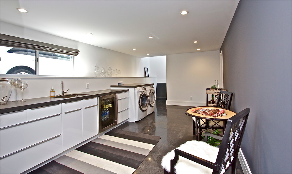 Example of a large mid-century modern concrete floor utility room design in San Francisco with an undermount sink, flat-panel cabinets, white cabinets, quartz countertops, gray walls and a side-by-side washer/dryer