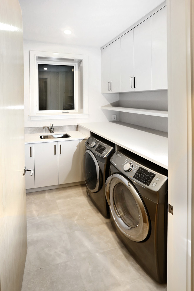 Diseño de cuarto de lavado en U contemporáneo pequeño con fregadero encastrado, puertas de armario blancas, encimera de cuarzo compacto, paredes blancas, suelo vinílico, lavadora y secadora juntas y suelo negro