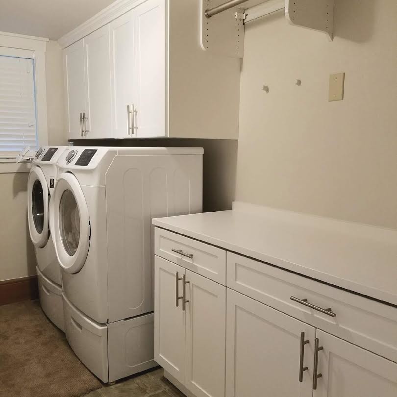 Example of a large classic single-wall ceramic tile and beige floor dedicated laundry room design in Seattle with shaker cabinets, white cabinets, solid surface countertops, white walls and a side-by-side washer/dryer