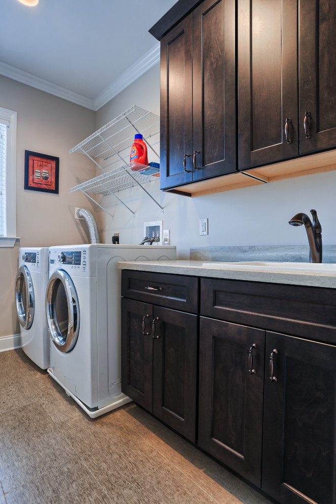 Klassisk inredning av en stor parallell tvättstuga enbart för tvätt, med luckor med infälld panel, skåp i mörkt trä, beige väggar och en tvättmaskin och torktumlare bredvid varandra