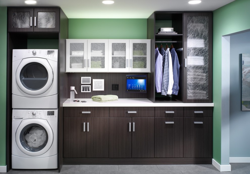 Diseño de cuarto de lavado de galera actual de tamaño medio con armarios con paneles lisos, puertas de armario de madera en tonos medios, encimera de madera y lavadora y secadora apiladas