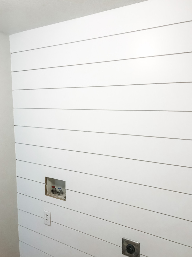 Inredning av ett lantligt litet grå linjärt grått grovkök, med öppna hyllor, vita skåp, träbänkskiva, vita väggar, klinkergolv i porslin, en tvättmaskin och torktumlare bredvid varandra och beiget golv