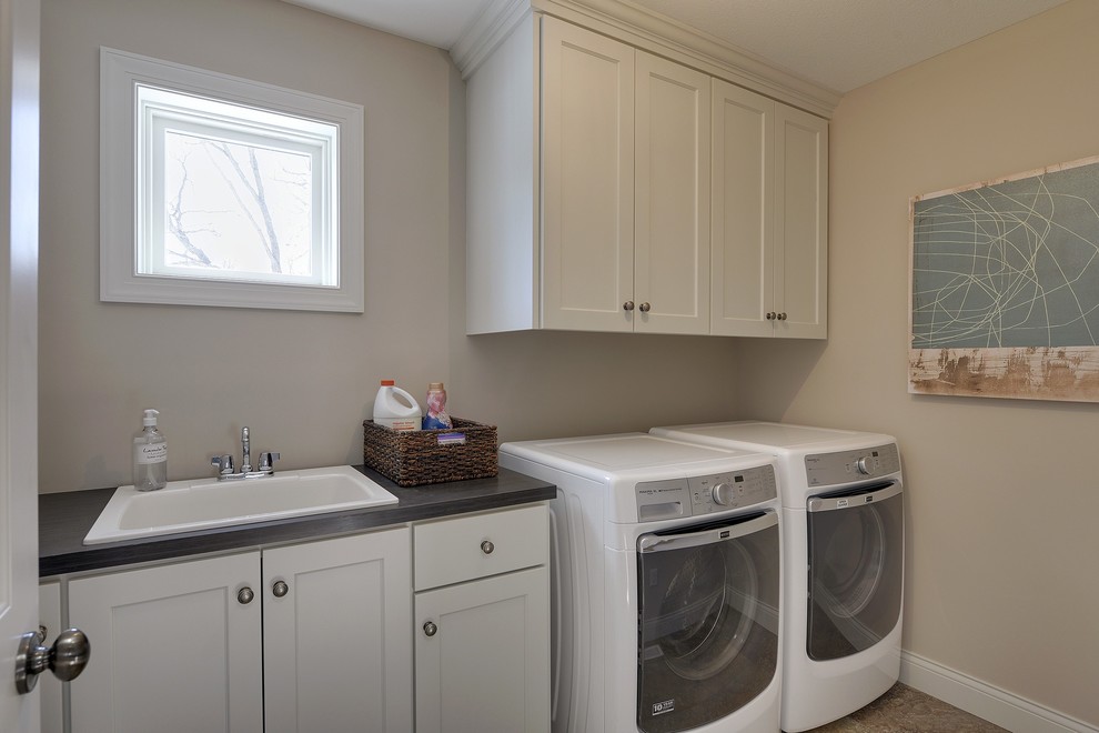 Inspiration for a large transitional single-wall ceramic tile dedicated laundry room remodel in Minneapolis with a drop-in sink, shaker cabinets, white cabinets, laminate countertops, beige walls and a side-by-side washer/dryer