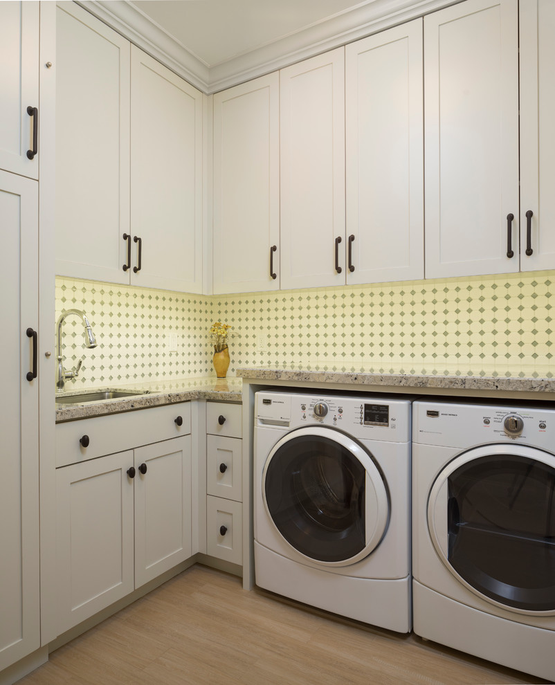 Foto di una grande sala lavanderia stile americano con lavello sottopiano, ante con riquadro incassato, ante bianche, top in granito e lavatrice e asciugatrice affiancate