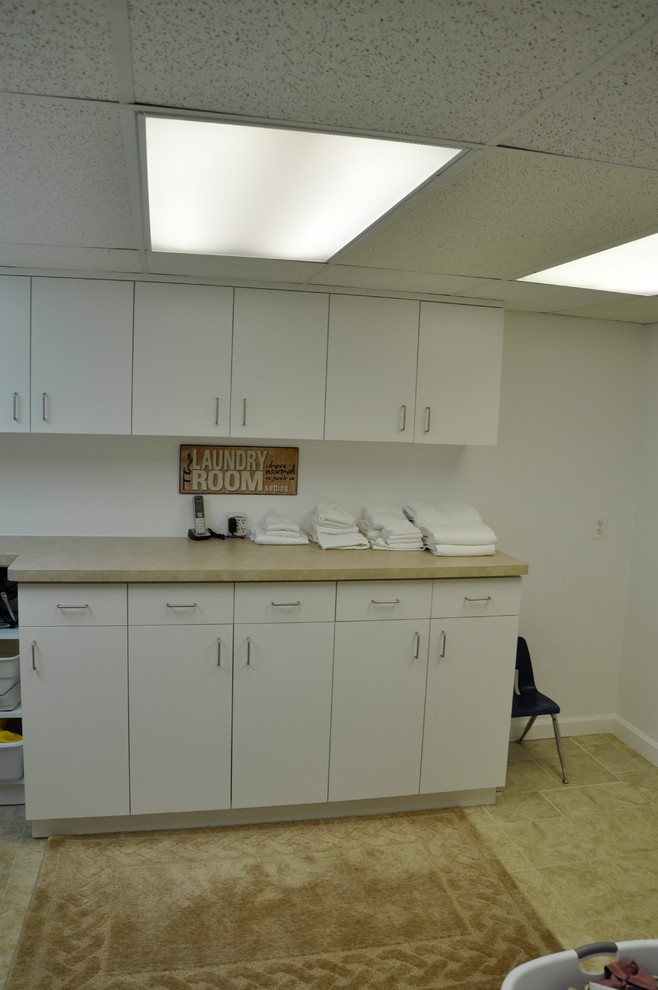 Dedicated laundry room - large single-wall dedicated laundry room idea in Detroit with flat-panel cabinets, white cabinets, laminate countertops and a side-by-side washer/dryer
