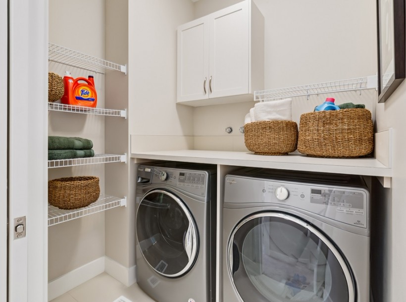 Immagine di una sala lavanderia design di medie dimensioni con ante bianche, top in laminato, pareti bianche, pavimento in gres porcellanato, lavatrice e asciugatrice affiancate e pavimento beige